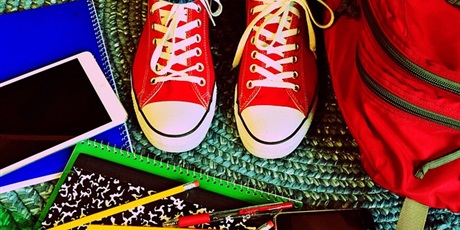 Powiększ grafikę: zdjęcie - czerwone trampki, plecak, zeszyty i długopisy na tle zielonego dywanika