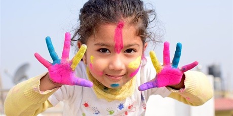 Powiększ grafikę: zdjęcie - dziewczynka z umazanymi farbami dłońmi i buzią