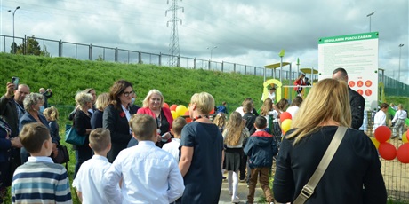 Powiększ grafikę: prezydent Dulkiewicz i dyrektor szkoły  w otoczeniu uczniów, nauczycieli i rodziców na placu zabaw przy szkole