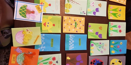 Powiększ grafikę: kartki wielkanocne wykonane przez uczniów rozłożone na stole