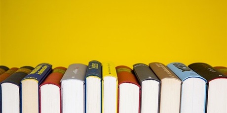 Powiększ grafikę: książki ustawione grzbietami do góry na tle żółtej ściany