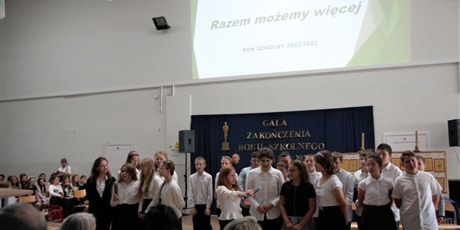 Powiększ grafikę: uczniowie klasy wykonują piosenkę podczas uroczystego zakończenie roku szkolnego 2022/23 na holu głównym